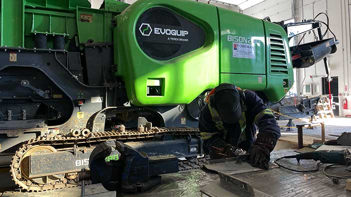 bison-380-shop-700x394px Serviceman working on Bison 280 crusher in Foreman equipment shop