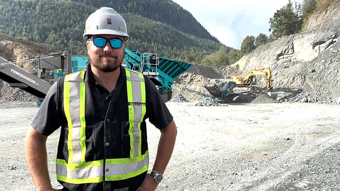 A worker wearing PPE, standing in front of machinery