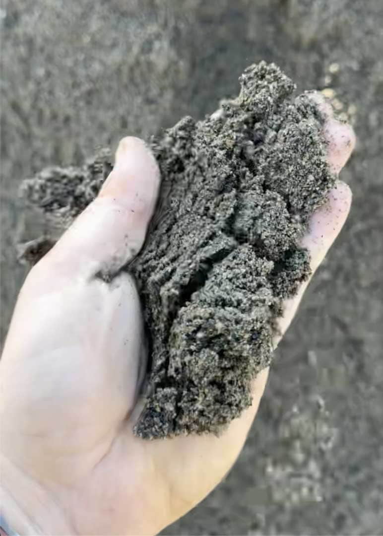 Close-up of soil sample held in hand for construction testing.