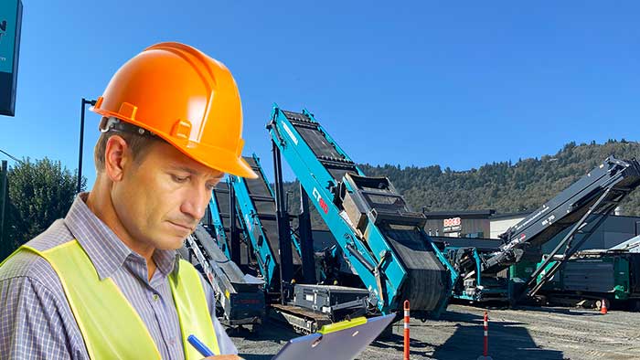 rental-page-intro-700x394px worker wearing a hardhat, holding a clipboard reviewing rental equipment